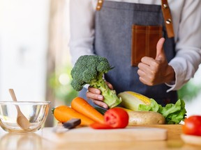 A woman chef holding and making thumb up to show good sign to a green broccoli with vegetables tray