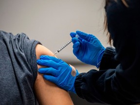 A man is inoculated with the Pfizer-BioNTech COVID-19 vaccine at La Colaborativa in Chelsea, Mass., Feb. 16, 2021.