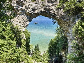 Three boats on Lake Huron are moored together underneath Arch Rock on Mackinac Island, Michigan.