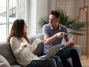 Young couple arguing about high bills with laptop and documents