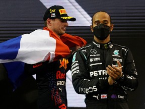 Red Bull's Max Verstappen celebrates winning the race and the world championship with the Netherlands flag on the podium as Mercedes' Lewis Hamilton looks dejected after finishing second in Abu Dhabi.