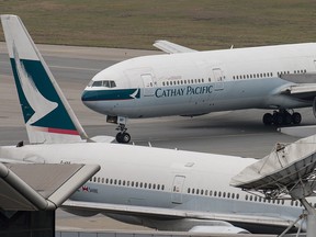 This file photo taken on March 15, 2017 shows a Cathay Pacific Boeing 777 passenger aircraft (top) taxiing past a stationary plane on the tarmac at the international airport in Hong Kong.