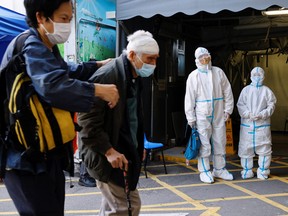 A patient and her relative wearing personal protective equipment wait outside the Accident and Emergency department in Hong Kong, March 4, 2022.