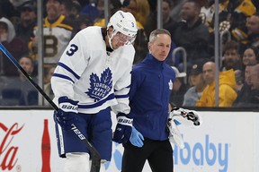 Maple Leafs' Justin Holl is led off the ice by a coach after being cut during the second period against the Boston Bruins at TD Garden.  WINSLOW TOWNSON/USA TODAY SPORTS