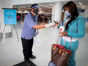 Travel Safely Ambassador Carlos Hernandez hands out a face masks to an airline passenger at LAX airport, as the global outbreak of COVID-19 continues, in Los Angeles, Calif., Aug. 4, 2020.