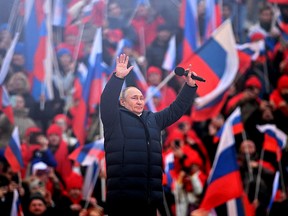 Russian President Vladimir Putin greets the audience as he attends a concert marking the eighth anniversary of Russia's annexation of Crimea at the Luzhniki stadium in Moscow on March 18, 2022.
