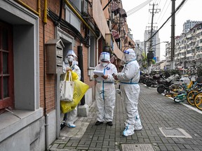 Health workers wearing protective gear as a measure against Covid-19 work along a street in Jing'an district in Shanghai on March 26, 2022.