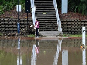 A woman makes her way next to spillover from the flooded Parramatta river at the ferry wharf in Sydney on February 23, 2022.