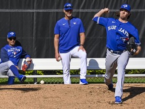 Toronto Blue Jays manager Charlie Montoyo (left) and pitching coach Pete Walker (centre) watch Kevin Gausman throw in the bullpen during a spring training workout on March 14, 2022, in Dunedin, Fla.