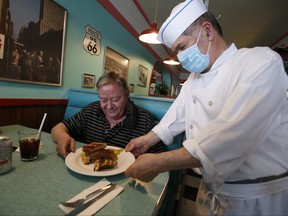 Peter Roubos owner of the Times Square Diner in Toronto serves up a famous Western sandwich to long-time customer John Kiely on March 1, 2022.