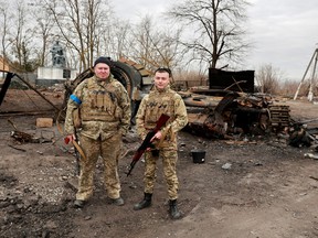 Ukrainian servicemen pose in front of what they say are destroyed military Russian vehicle and equipment in the village of Lukianivka, Ukraine March 28, 2022.