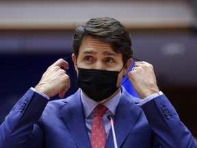 Prime Minister Justin Trudeau removes his face mask to address European lawmakers amid Russia's invasion of Ukraine, in Brussels, Belgium, March 23, 2022.