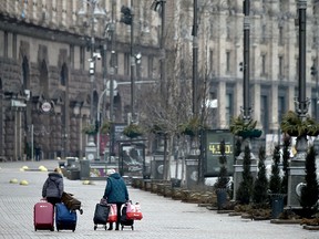 Women carry their belongings as they walk in a deserted street of Ukrainian capital of Kyiv on March 1, 2022.