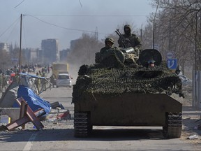 Service members of pro-Russian troops in uniforms without insignia drive an armoured vehicle during Ukraine-Russia conflict in the besieged southern port city of Mariupol, Ukraine, March 19, 2022.