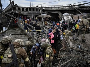 People cross a destroyed bridge as they evacuate the city of Irpin, northwest of Kyiv, during heavy shelling and bombing on Saturday, March 5, 2022.