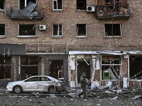 A Ukranian serviceman walks in front of a destroyed apartment building after it was shelled in Kyiv, Monday, March 14, 2022.