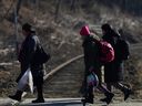 Ukrainische Flüchtlinge, die vor der russischen Invasion in der Ukraine fliehen, gehen nach dem Überqueren der Grenze zwischen der Ukraine und Polen in Kroscienko, Polen, Dienstag, 22. März 2022.