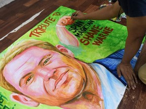 An art school teacher makes a painting to pay homage to the former Australian cricketer Shane Warne, in Mumbai on March 5, 2022, after Warne died on March 4 of a suspected heart attack.