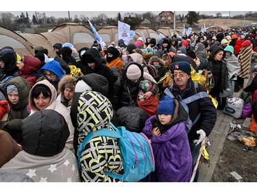 Refugees stand in line in the cold as they wait to be transferred to a train station after crossing the Ukrainian border into Poland, at the Medyka border crossing in Poland, on March 7, 2022.