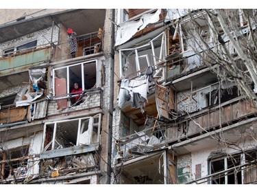 A resident uses a dustpan and broom (top) to clear the debris from a flat, as another looks out of the destroyed front of a room, in a multi-storey building that was badly damaged as a result of Russian missile explosion after it was shot down over the city by Ukrainian air defence on March 6, in Kramatorsk on March 7, 2022.