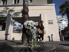 A pedestrian walks past white flowers next to the building where five people appeared to have jumped from their apartment in Montreux, western Switzerland, on March 24, 2022.