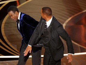 Will Smith (R) hits Chris Rock as Rock spoke on stage during the 94th Academy Awards in Hollywood, Los Angeles, California, U.S., March 27, 2022.