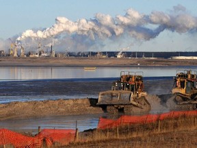 Workers use heavy machinery in the tailings pond at the Syncrude oil sands extraction facility near the town of Fort McMurray in Alberta Province, Canada on October 25, 2009.