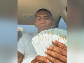Screenshot of selfie video of man counting out $100 bills.