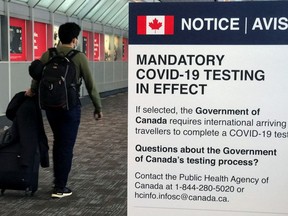 A traveler walks past a "Mandatory COVID-19 Testing" sign at Pearson International Airport during the coronavirus disease (COVID-19) pandemic of Toronto, Ontario, Canada, December 18, 2021.