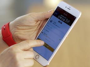 An employee uses an Apple iPhone to demonstrate to reporters how to pay using the Apple Pay service at an Apple store in Beijing, China, February 17, 2016.