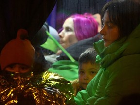 People sit in a shuttle bus after crossing the border from Ukraine to Poland with people fleeing the Russian invasion of Ukraine at the border checkpoint in Medyka, Poland, March 7, 2022.
