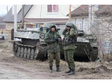 Service members of pro-Russian troops in uniforms without insignia stand next to an armoured vehicle in the separatist-controlled settlement of Buhas (Bugas), as Russia's invasion of Ukraine continues, in the Donetsk region, Ukraine March 1, 2022.