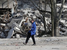 A local resident carries a cage while walking past an apartment building destroyed during Ukraine-Russia conflict in the besieged southern port city of Mariupol, Ukraine March 31, 2022.