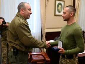 Ukrainian service member Roman Gribov receives a medal from the head of Cherkasy Regional Military Administration, Ihor Taburets, in Cherkasy, Ukraine. The photo was  released March 29, 2022.