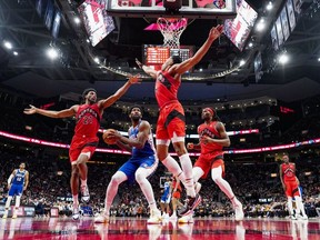 Joel Embiid of the Philadelphia 76ers is guarded by Scottie Barnes, Thaddeus Young, and Precious Achiuwa of the Toronto Raptors during the second half of their basketball game at the Scotiabank Arena.