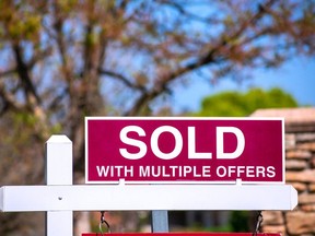 SOLD With Multiple Offers real estate sign near purchased house indicates hot seller's market in the desired neighborhood.  Blurred outdoor background.  Bidding war concept.