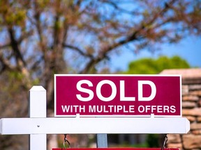 SOLD With Multiple Offers real estate sign near purchased house indicates hot seller's market in the desired neighborhood. Blurred outdoor background. Bidding war concept.