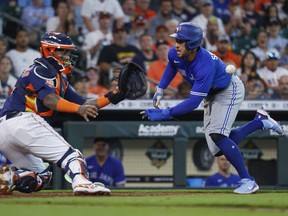 Blue Jays’ George Springer dives around Astros catcher Martin Maldonado to score a run during the fourth inning yesterday in Houston. The Jays lost in 10 innings, but still took the three-game set 2-1. They are 5-0-1 in their first six series.