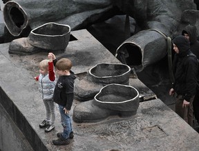 Children pose for a photo on the pedestal of the Soviet monument to Ukraine-Russia friendship dismantled by workers in Kyiv on April 26, 2022, amid Russian invasion of Ukraine. (Photo by GENYA SAVILOV/AFP via Getty Images)