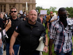 In this file photo taken on April 18, 2020 Infowars host Alex Jones marches with protesters during the "Reopen America" rally at the State Capitol in Austin, Texas.