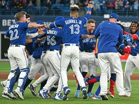 Toronto Blue Jays players surround left fielder Raimel Tapia as they celebrate his walk off sacrifice fly that scored the winning run against the Boston Red Sox in the 10th inning at Rogers Centre April 26, 2022..