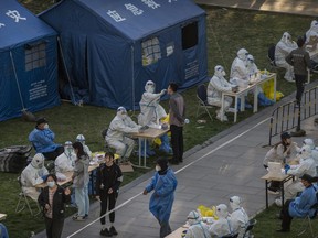 Health workers wear protective suits as employees from local high tech companies are given a nucleic acid tests to detect COVID-19 at a makeshift testing site in Haidian District on April 26, 2022 in Beijing.