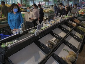 People shop for vegetables as some shelves are nearly empty after items being bought out at a supermarket in Chaoyang District on April 25, 2022 in Beijing.