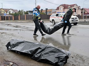 Kommunalarbeiter tragen Leichensäcke in der Stadt Bucha, unweit der ukrainischen Hauptstadt Kiew, am 3. April 2022.