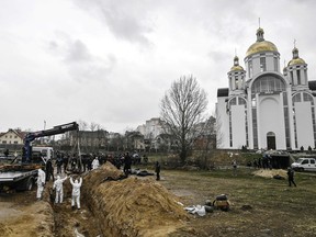 Ukrainian investigators exhume bodies from a mass grave in the grounds of the St Andrew church in the town of Bucha, northwest of Kyiv, on April 8, 2022.