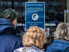 A sign on the door of a Berlin department store reads: "From now on, you may shop safely without wearing a mask", as shoppers walk inside on April 1, 2022.