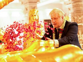 British Prime Minister Boris Johnson throws petals at a shrine during his visit to Akshardham Temple in Ahmedabad, India, Thursday, April 21, 2022.