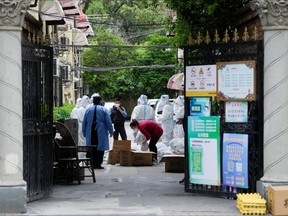 Workers in protective suits  are seen at a residential area under lockdown amid the COVID-19 pandemic in Shanghai, April 15, 2022.