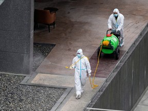 Workers in protective suit spray disinfectant at a community, during the lockdown to curb the spread of COVID-19 in Shanghai, China, April 5, 2022.