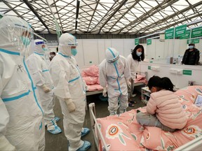 Medical workers in protective suits check a child patient as they conduct ward rounds at Shanghai New International Exhibition Hall, which has been turned into a makeshift hospital for COVID-19 in Shanghai, April 9, 2022.